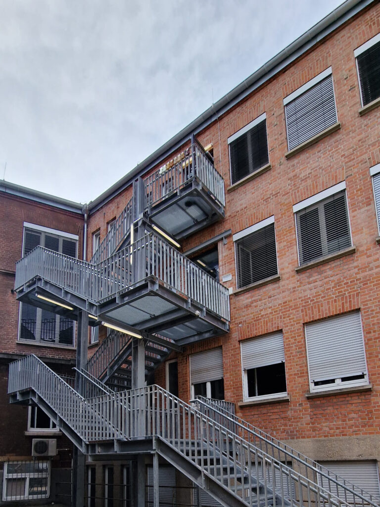 Türen mit Stahltreppe in Kombination an einem Backsteingebäude